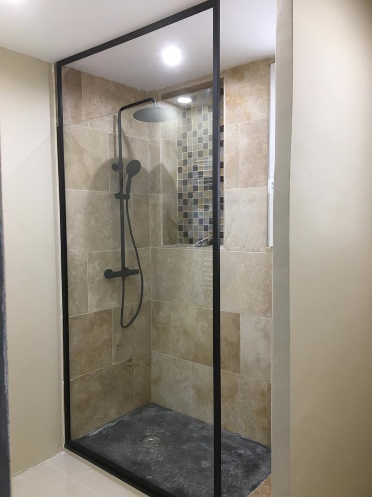 Douche avec parois vitrées et murs carrelés